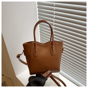 Detail of caramel brown matte leather bucket bag with embossed Fashion lettering and handles