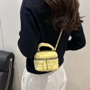 Bright yellow quilted mini box crossbody bag with gold chain strap on a model