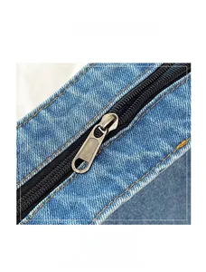 Detail of smooth silver zipper on washed denim canvas with orange contrast stitching