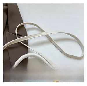 Detail of white lychee texture shoulder strap and handle with gold hardware accents