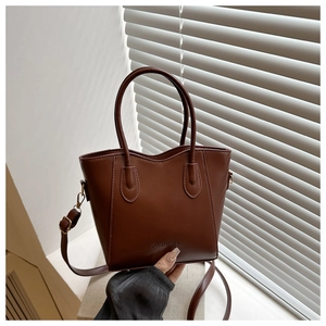 Detail of a brown bucket bag showing the fashion logo and circular top handles