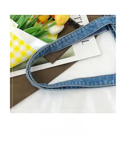 Detail shot of sturdy double-stitched light blue denim handles on a large tote bag