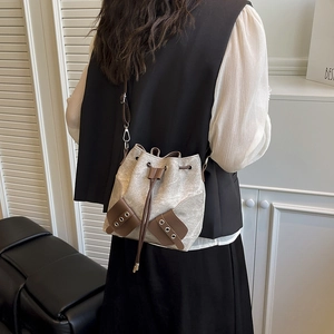 Beige canvas bucket bag with brown leather drawstring and metal eyelets on model