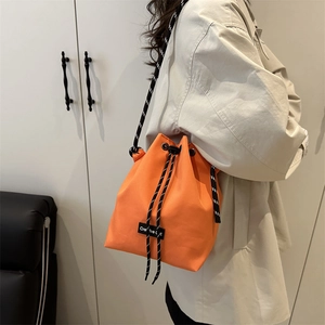 Dettaglio della borsa a secchiello arancione con etichetta Creative Cat e tracolla