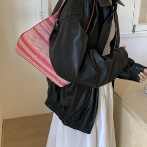 Handmade woven tote bag with pink and orange stripes worn over shoulder by model