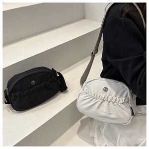 Detail of minimalist pleated crossbody bags in black and cream with M logo and wide strap