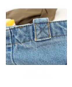 Detailed close-up of yellow reinforced cross-stitching on durable blue denim tote bag