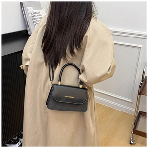Detail of elegant black patchwork handbag with woven texture and gold fashion lettering