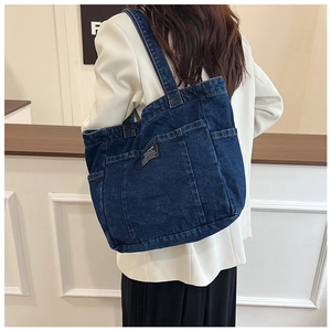 Detail view of denim tote bag with side pockets and functional compartments on model