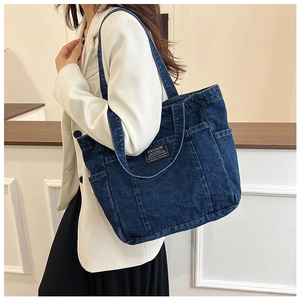 Detailed view of dark blue denim tote bag featuring utility pockets and fashion label