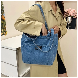 Lifestyle shot of large blue denim tote bag with multiple pockets and functional shoulder strap