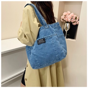 Detail of blue denim tote bag with functional pockets and Fashion Instinct woven label