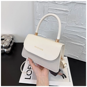 Detail of elegant white crossbody bag with woven texture and gold hardware accents