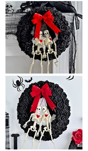 Macro detail of Gothic wreath with black roses, red bow and skeleton figures