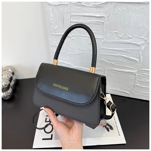 Detail of elegant black patchwork handbag with gold lettering and diamond texture