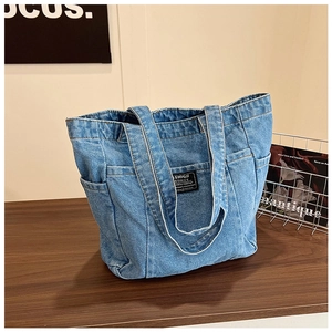 Close-up of vintage light blue denim tote bag with functional pockets on a wooden desk