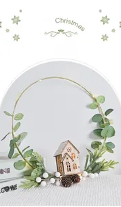 Detail of Christmas wreath with golden ring, pine cones, and lighted miniature wooden house