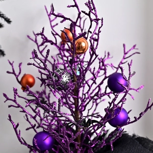 Purple glitter Halloween decorative tree with orange ornaments and black spider web baubles