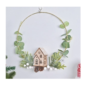 Detail of a gold metal Christmas wreath with a wooden house, pine cones and white berries