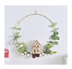 Detail of Christmas wreath with golden ring, pine cones, and a small wooden house model