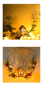 Detail of Christmas wreath with glowing wooden house, red berries and pine cones