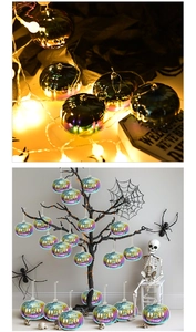 Close-up of iridescent Halloween pumpkin ornaments with glowing face cutouts for trees
