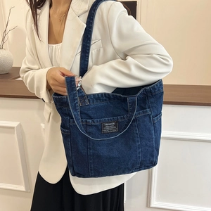Large dark blue denim tote bag with functional exterior pockets and shoulder straps