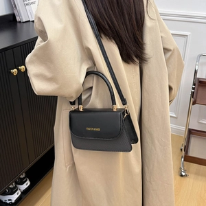 Elegant black crossbody bag with contrast texture shown on a model in a minimal setting