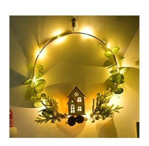 Detail of Christmas wreath with warm LED lights, pine cones, and a wooden house pendant
