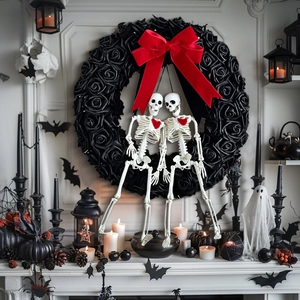 Gothic Halloween wreath with black roses, red bow, and skeleton couple on a white wall