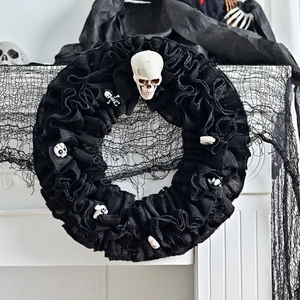 Gothic Halloween wreath featuring black ruffled fabric and multiple white skull decorations