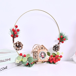 Golden Christmas wreath with wooden fairy cottage, red berries and pine cones decor