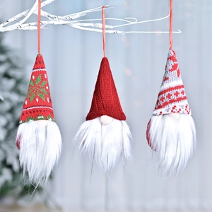 Three Nordic Christmas gnome ornaments with knitted hats hanging on a white branch