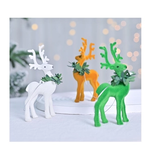 Close-up of three flocked reindeer ornaments in white, orange and green for Christmas