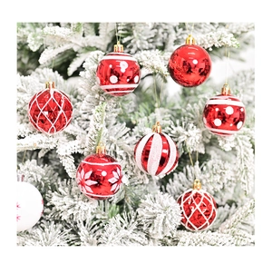Bolas de Navidad rojas con patrones blancos colgadas en un árbol de Navidad nevado