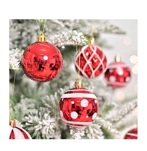 Primer plano de bolas de Navidad rojas con patrones blancos en una rama nevada