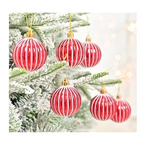 Detail van een rode gestreepte kerstbal aan een besneeuwde tak met warme lichten