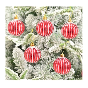 Detailopname van rood-wit gestreepte kerstballen aan een besneeuwde boomtak