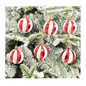 Close-up of red and white striped Christmas ornaments on snowy pine branches