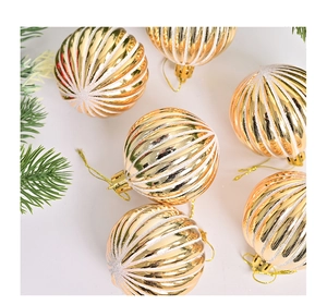Detail van 6 gouden kerstballen met witte glittersperalen en groene dennennaalden