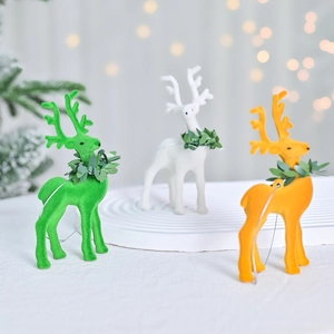 Three flocked Christmas reindeer figurines in green, white and orange with leaf collars