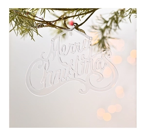 Gros plan d'un ornement de Noël en acrylique transparent sur une branche de pin