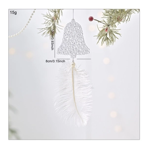 White bell ornament with feather and pearl detail hanging on a Christmas tree branch