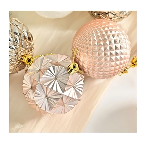 Macro shot of pink and silver Christmas balls with faceted geometric texture and gold strings
