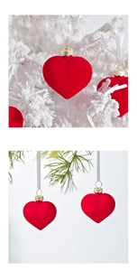 Macro detail of red flocked heart ornaments with gold caps on a snowy Christmas tree