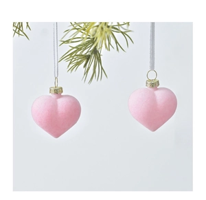 Pink frosted heart ornaments with golden caps hanging on green pine branches