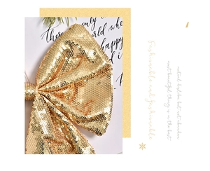 Close-up of golden sequined Christmas tree bow with shimmering metallic texture decorations