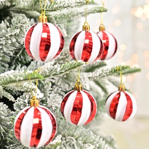 Red and white striped Christmas ball ornaments hanging on a snowy tree with bokeh lights