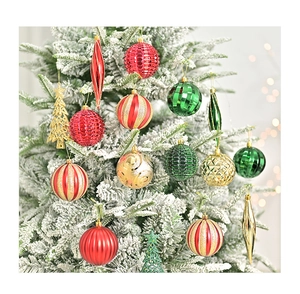 Close-up of assorted red, gold and green Christmas ornaments hanging on a snowy pine tree