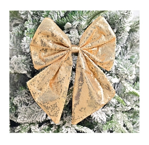 Close-up of golden sequin Christmas bow decoration hanging on a snowy pine branch
